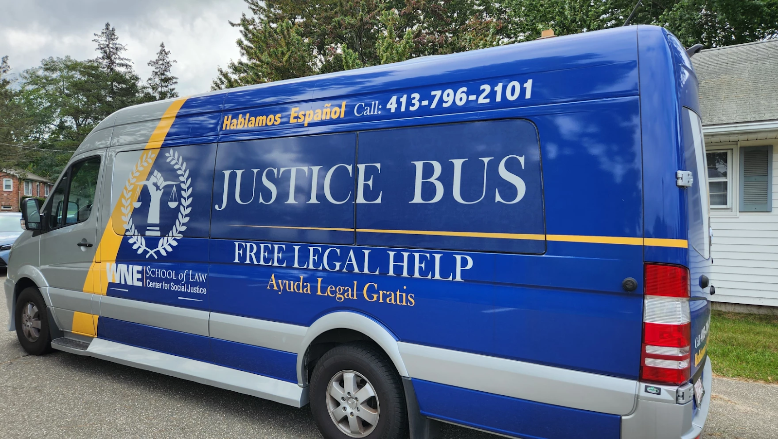 Western New England University's bright blue Justice Bus, a large van with the school's logo and legal help information.